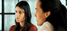 two women are talking to each other in a room .