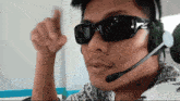 a man wearing sunglasses and a microphone giving a thumbs up sign