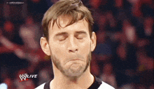 a man with a beard is making a funny face while watching a wrestling match on wlive