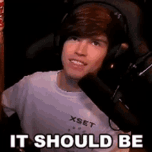 a man wearing headphones is sitting in front of a microphone with the words it should be written below him
