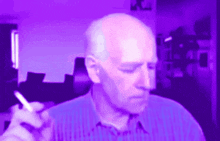 a man in a blue shirt is smoking a cigarette in a purple room