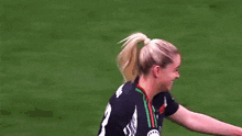 two female soccer players hugging each other on a field .