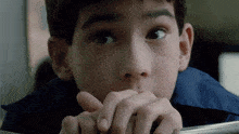 a close up of a child 's face with his hands on his face