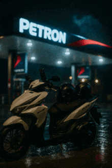 a white motorcycle is parked in front of a petron gas station