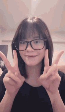a young woman wearing glasses is giving a peace sign