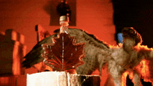 a bottle of maple syrup sits on a stump in front of a bird
