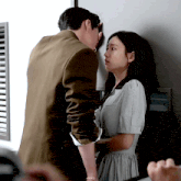 a man and a woman are kissing against a wall