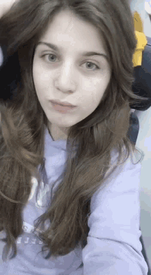 a girl with long hair is wearing a purple sweatshirt that says guess
