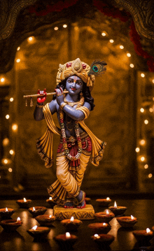 a statue of krishna playing a flute with candles in the background