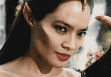 a close up of a woman 's face with a dragon 's horn on her head