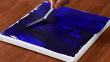a person is applying blue paint to a canvas