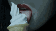 a close up of a woman eating an ice cream cone with her tongue out .