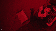 a man singing into a microphone in a red room with the letter d below him