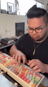 a man wearing glasses is typing on a keyboard