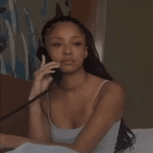a woman is sitting in bed talking on a telephone .
