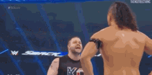 two men are wrestling in a wrestling ring with a referee watching .