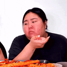 a woman with acne on her face sits at a table eating food