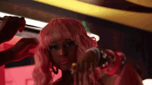 a woman wearing a pink wig is getting her hair done by a man .
