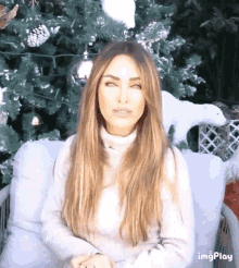 a woman with long hair is sitting in front of a christmas tree with a polar bear in a basket