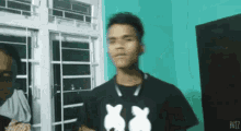 a young man wearing a mickey mouse t-shirt is standing in a room .