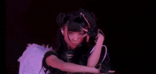 a girl in a gothic costume is making a funny face while holding her hand to her face .