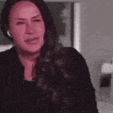 a woman with long hair is sitting down with her eyes closed and a serious look on her face .