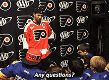 a man wearing a red jersey with the number 8 on it stands in front of a group of kids asking any questions