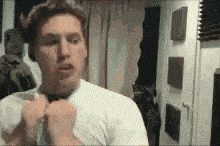 a man in a white shirt adjusts his tie