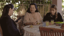 three women sitting at a table with a hd logo on the bottom