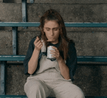 a woman sitting on a bench with a can of soda