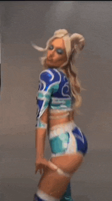 a woman in a blue and white outfit is kicking a ball