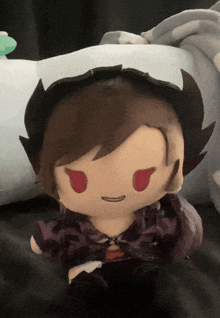a stuffed doll with red eyes is sitting on a pillow