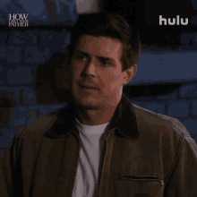 a man standing in front of a brick wall with the words how i met your father on the bottom right