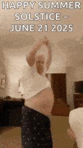 a man is standing in a living room with his arms in the air .