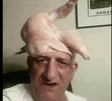 a man is wearing a chicken on his head and making a funny face .