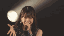 a woman holds a microphone in her right hand and smiles