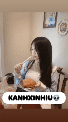 a girl eating a croissant with a kanhxinhiu sticker on the bottom