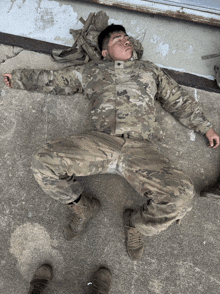 a soldier in a camouflage uniform is laying on the ground