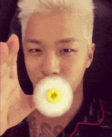 a man with a tattoo on his neck blowing a bubble with a yellow button on it