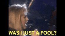 a woman singing into a microphone with the words " was i just a fool " behind her