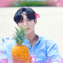a young man with a flower in his hair holds a pineapple