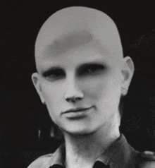 a man with a bald head and no eyebrows is smiling in a black and white photo .