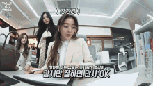 a woman in a suit sits at a desk with a bottle of water on it