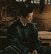 a man in a green robe is sitting in a dark room