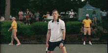a man holding a tennis racquet on a tennis court in front of a crowd