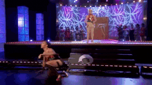 a woman in a bikini is dancing on a stage while a group of people watch .