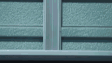 a close up of a window with a metal frame and a blue wall in the background .
