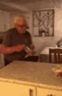 a man is standing in a kitchen holding a bottle of something .