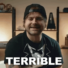 a man wearing a hat and a bow tie is smiling with the word terrible behind him .