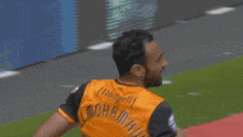 a man in a soccer uniform is running on a red field .